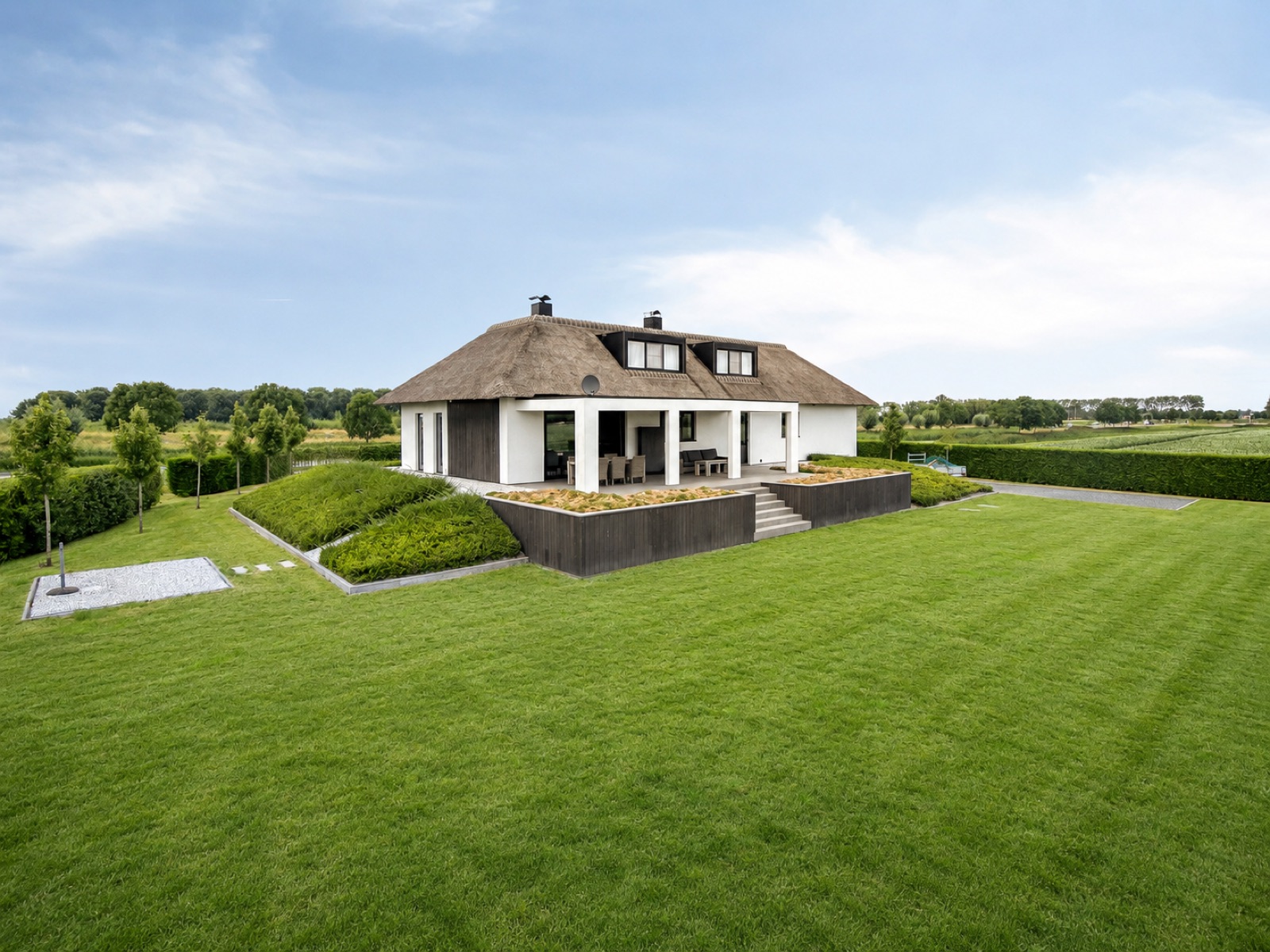 De villa met rieten dak, terras en weelderige tuin op het landgoed